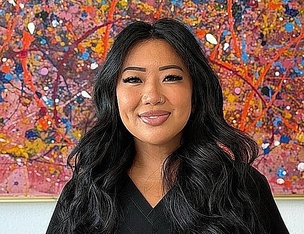 Smiling woman with long black hair and art.