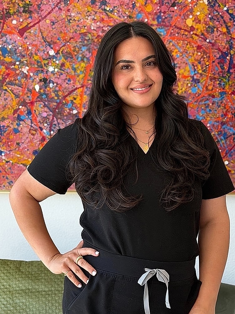 Woman smiling in front of colorful abstract art.