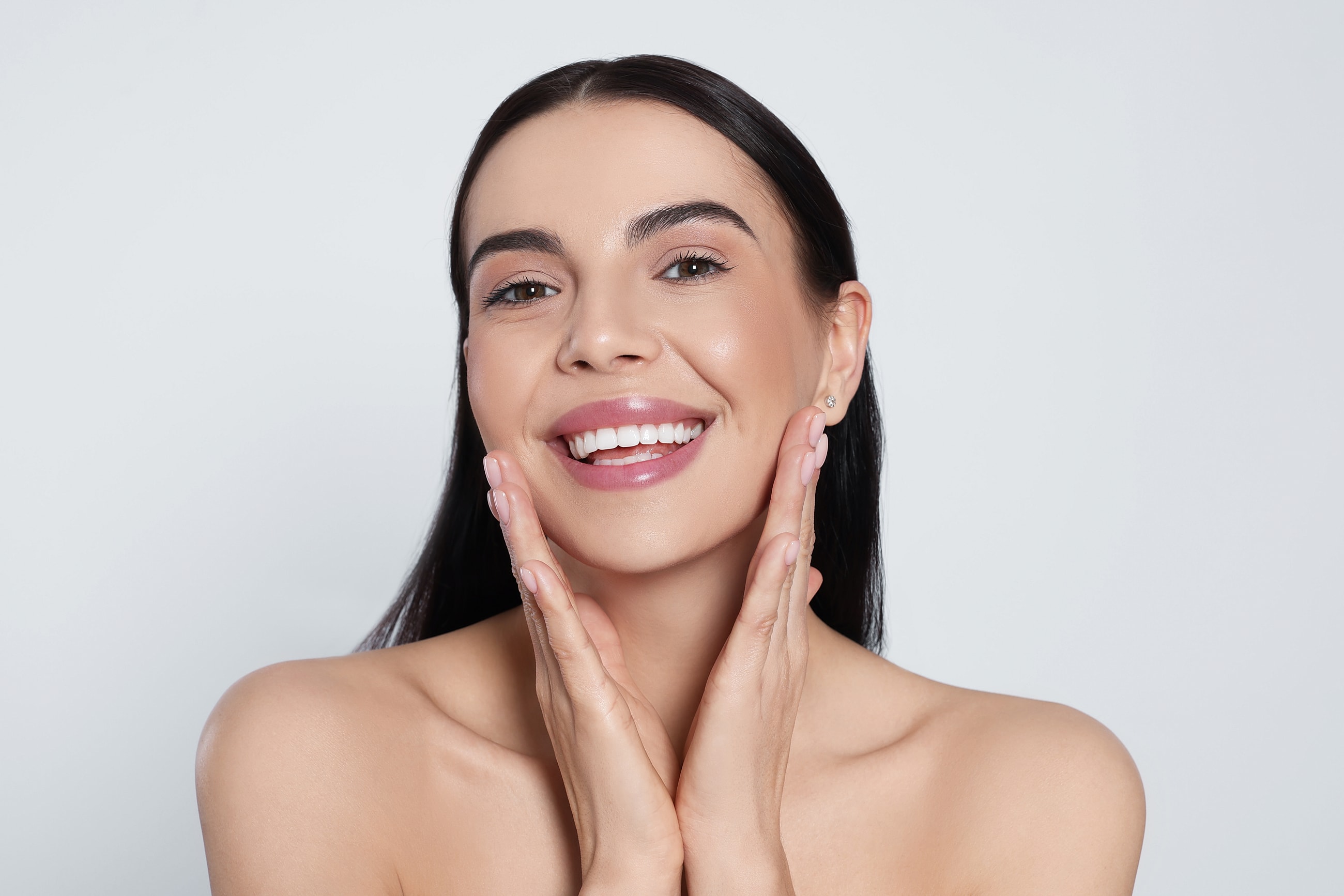 Smiling woman with healthy skin, hands on face.